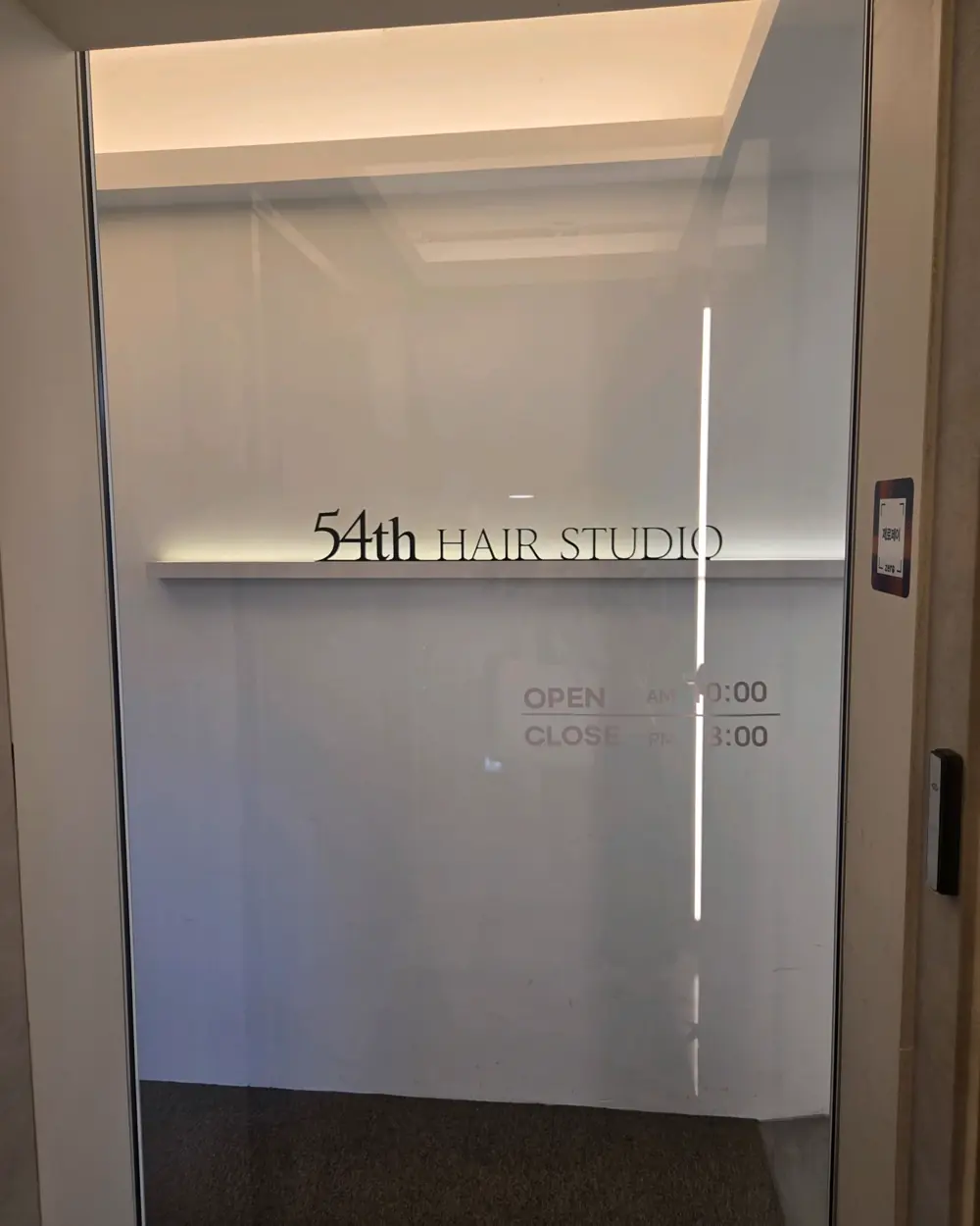 54th HAIR STUDIO 사인이 붙은 매장 입구 유리문